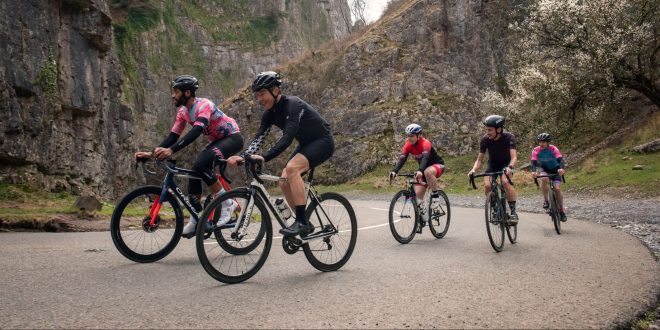 A group of five cyclists on a road with a mountainous backdrop
